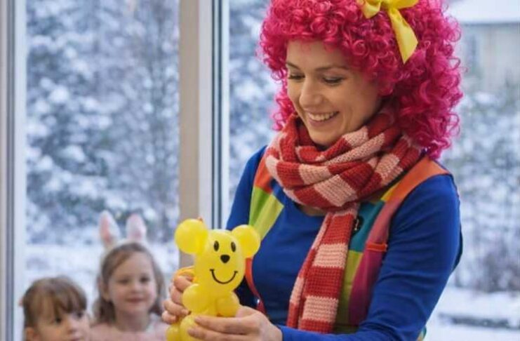 Animator dla dzieci przygotowuje balonowe zwierzątko podczas zimowych animacji dla najmłodszych